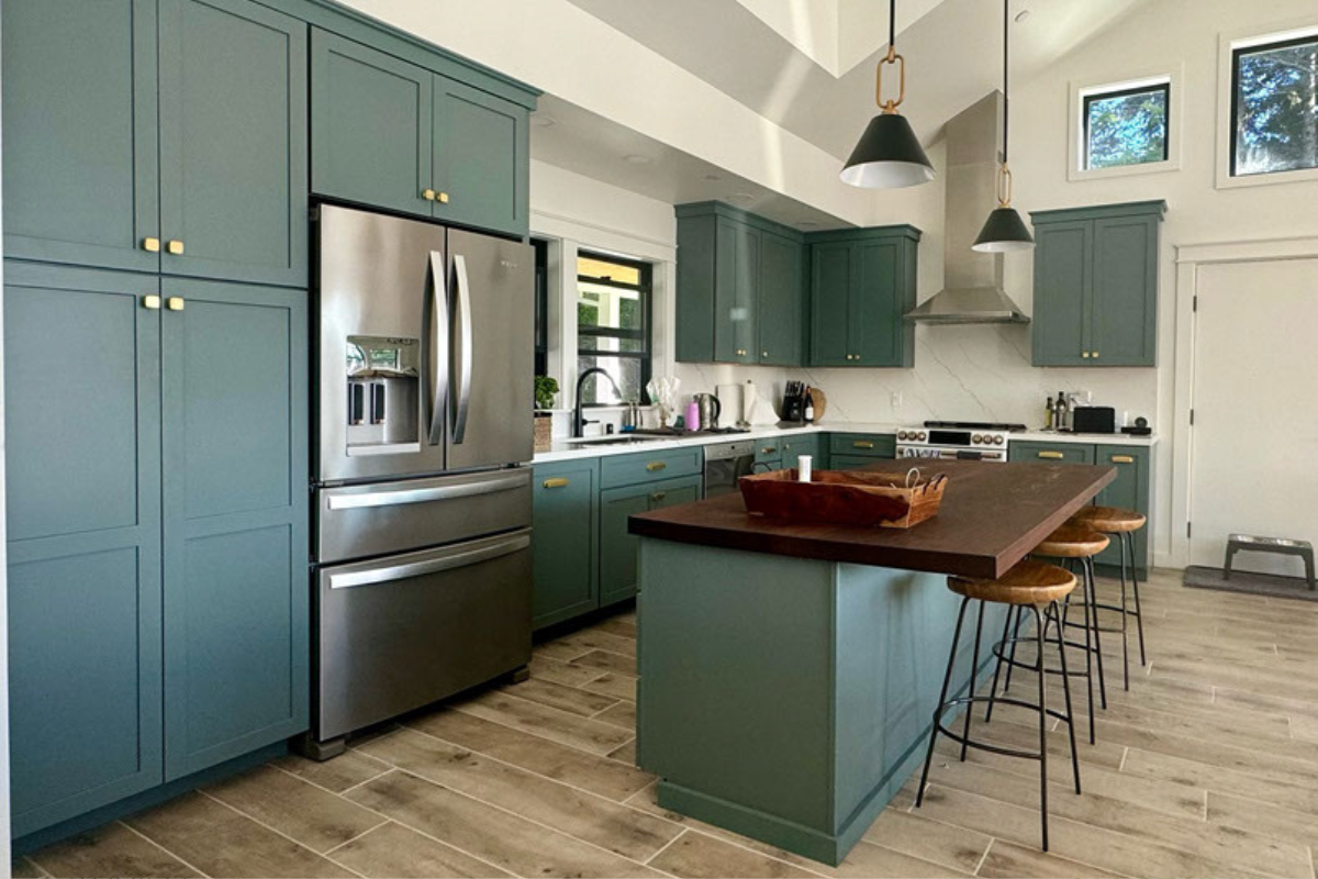 Turquoise shaker kitchen design with gold hardware, dark butcher block countertops and light flooring