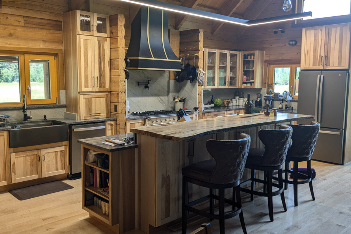 Rustic hickory kitchen design with shaker cabinets and a black hood and farm sink