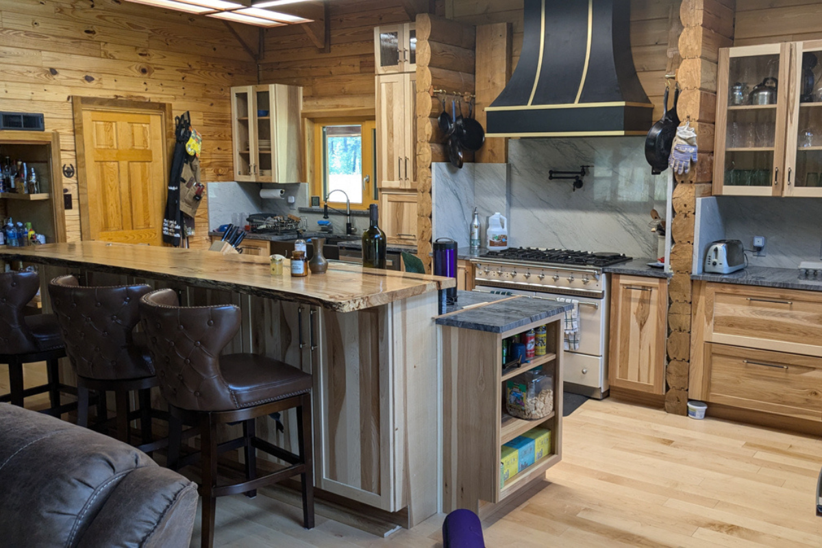 Rustic hickory kitchen design with shaker cabinets and a black hood and farm sink