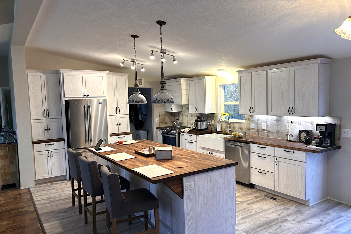 L-shaped white-washed shaker kitchen design with large center island and butcher block countertops in farmhouse style