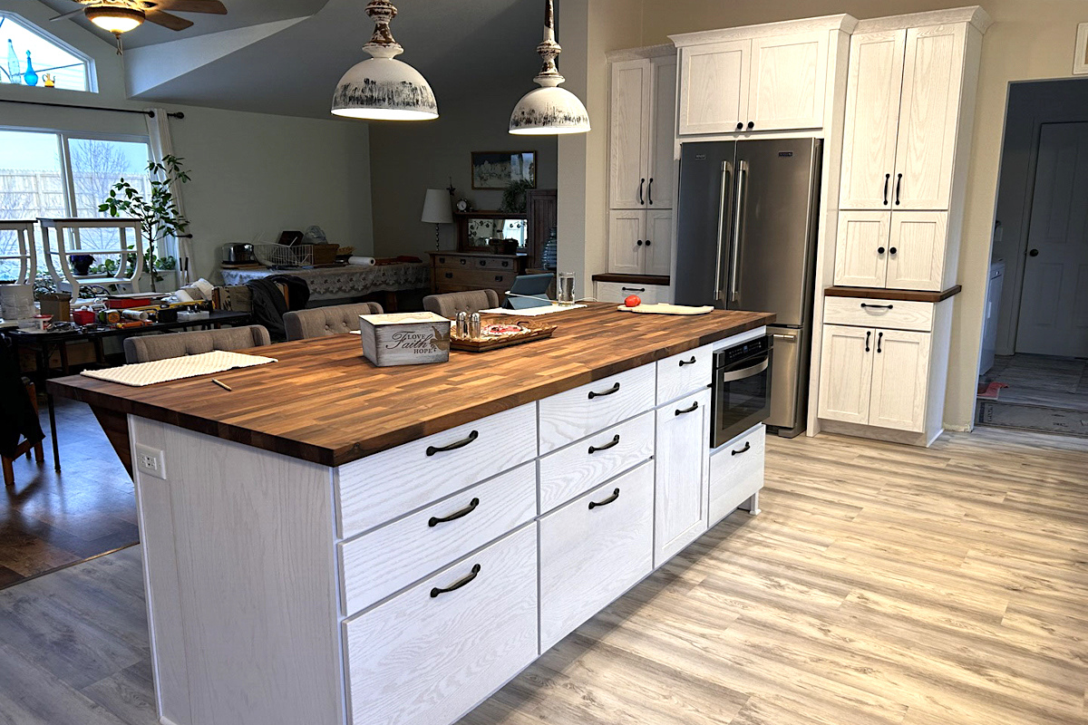 White-washed kitchen island with slab doors, black cabinet hardware and butcher block countertops