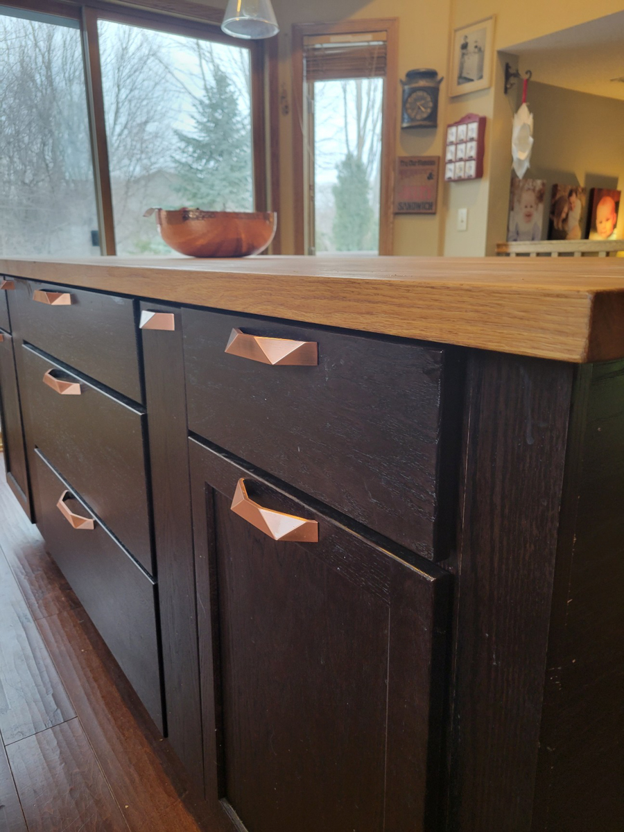 Black shaker island cabinets with baseboard molding and geometric brushed nickel hardware 