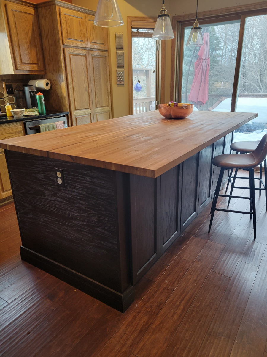 Black shaker island cabinets with baseboard molding and geometric brushed nickel hardware 