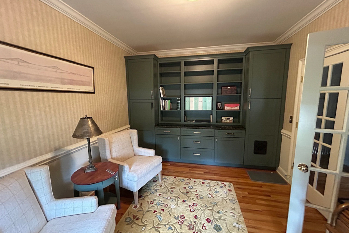 Dark green shaker cabinets in a den for book storage 