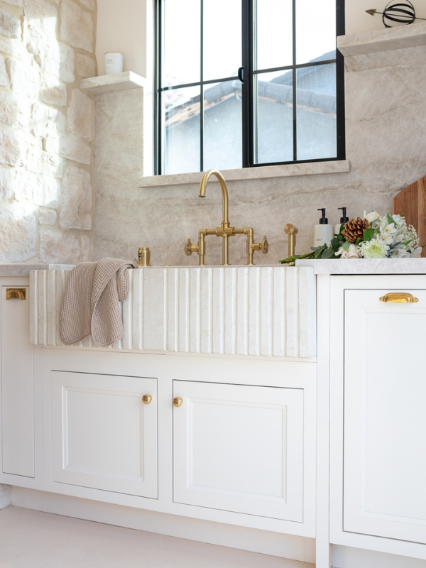 White inset kitchen cabinets with a fluted white farmhouse sink and a black framed window above