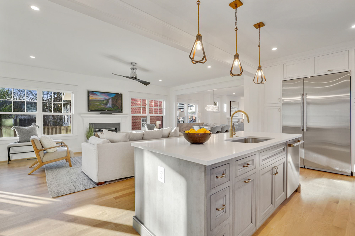 Stacked white shaker inset kitchen cabinets with a light gray stained island and white quartz countertops