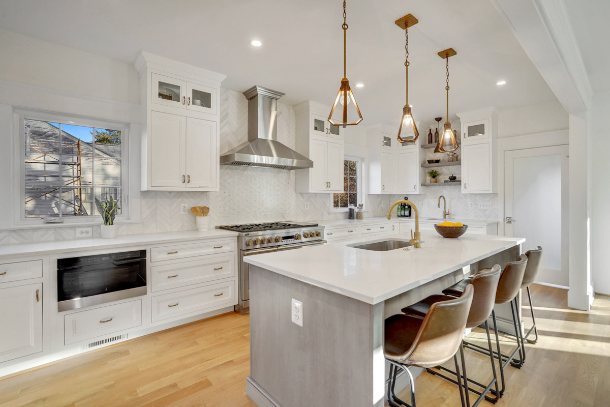 Stacked white shaker inset kitchen cabinets with a light gray stained island and white quartz countertops