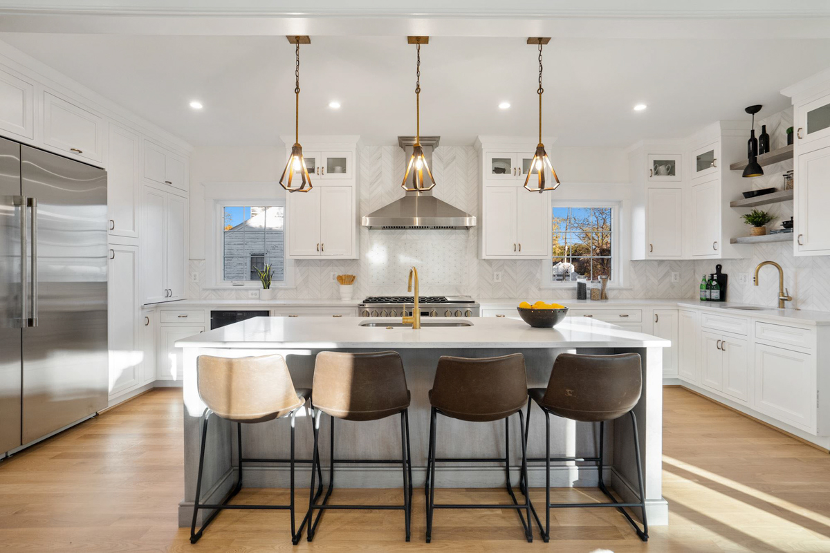 Stacked white shaker inset kitchen cabinets with a light gray stained island and white quartz countertops