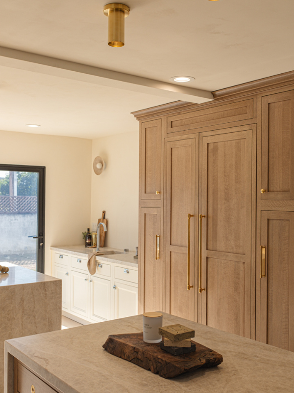 Two wood inset kitchen islands in front of a paneled refrigerator wall in the same light wood finish