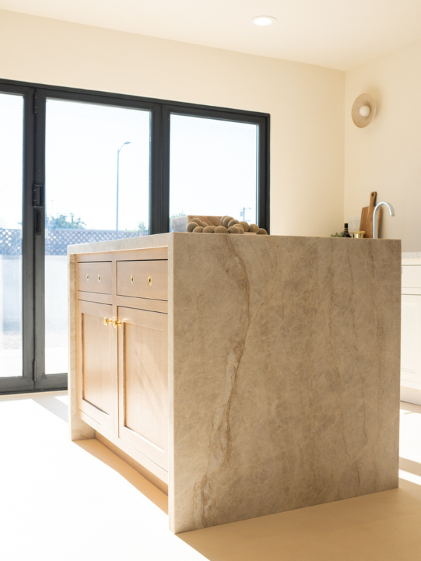 Light wood kitchen island with inset shaker door style, brass hardware and waterfall quartzite countertops