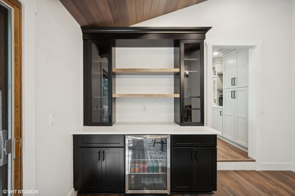 Black shaker bar cabinets with glass inserts and wood floating shelves between