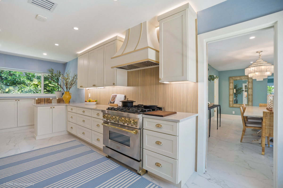 Soft white shaker kitchen cabinets with brass hardware and a modern wood slat backsplash