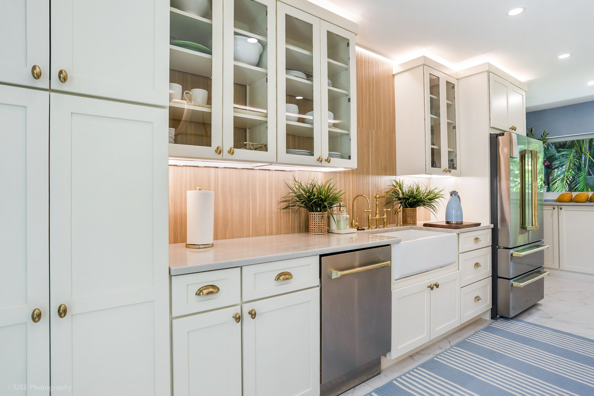 Soft white shaker kitchen cabinets with brass hardware and a modern wood slat backsplash