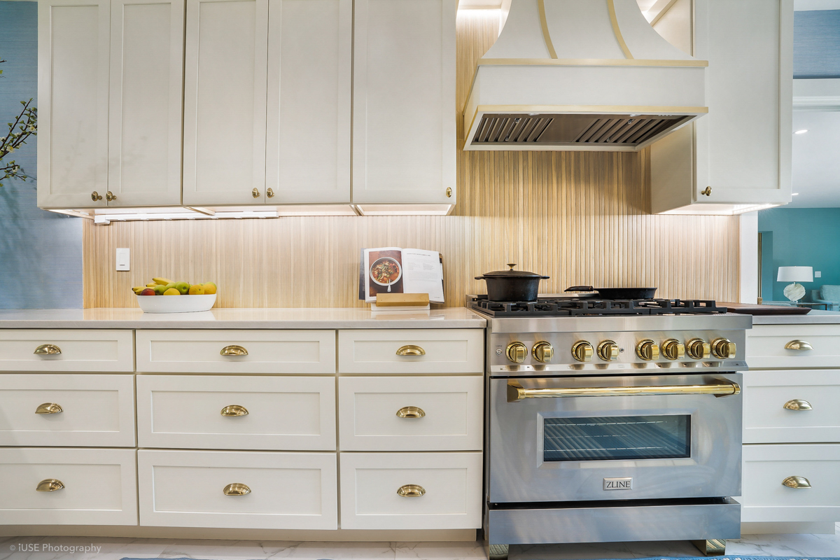 Soft white shaker kitchen cabinets with brass hardware and a modern wood slat backsplash