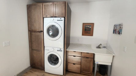 Dark wood shaker laundry room with a tall utility cabinet on the left and sink with countertop on the right