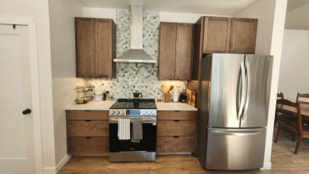 One-wall dark wood shaker kitchen design with a large island and white quartz countertops