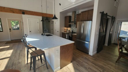 One-wall dark wood shaker kitchen design with a large island and white quartz countertops