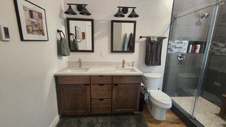 Rustic double vanity in dark wood shaker door style with light cream quartz countertops