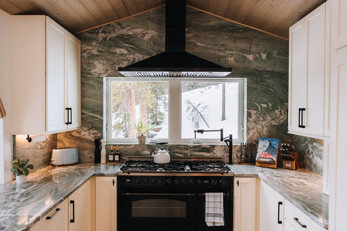 U-shaped white shaker kitchen design with modern black handles and green natural stone countertops and slab backsplash