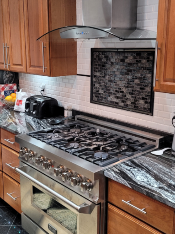 Raised panel cherry wood kitchen cabinets with black granite countertops and a waterfall edge