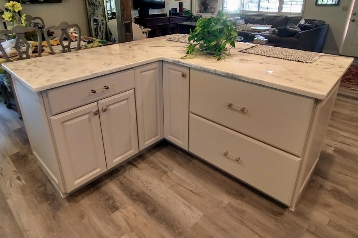 L-shaped kitchen design with L-shaped island in cream colored raised panel kitchen cabinets