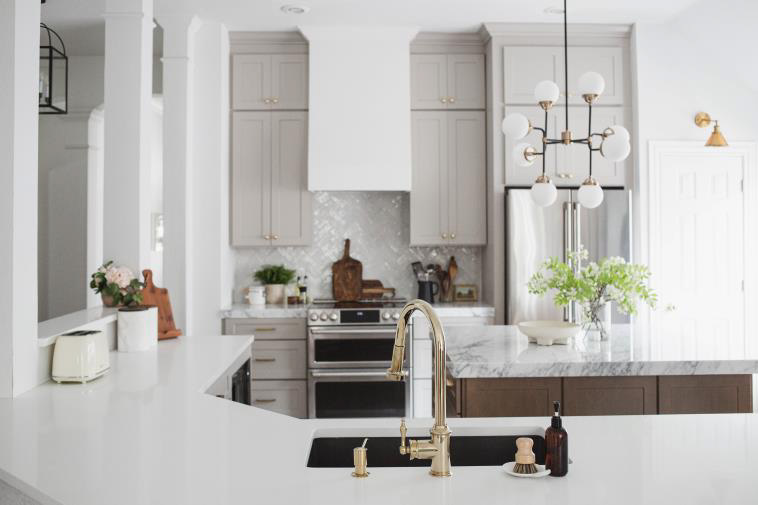 Light gray kitchen cabinets used with golden paint hardware. Gray and white textured countertops light up the look of the kitchen.