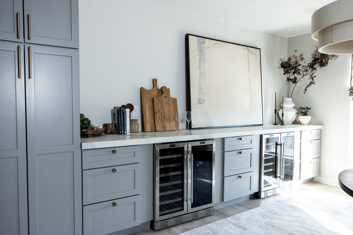 Built-in dining room sideboard in light gray shaker base cabinets with gold cabinet hardware and white quartz countertops