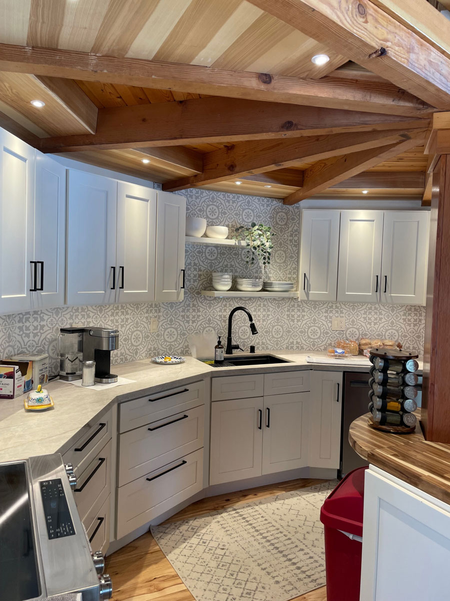 White shaker rustic farmhouse kitchen design in semi-circle shape and center island with wood beam on top and  wood beam ceiling with loft above