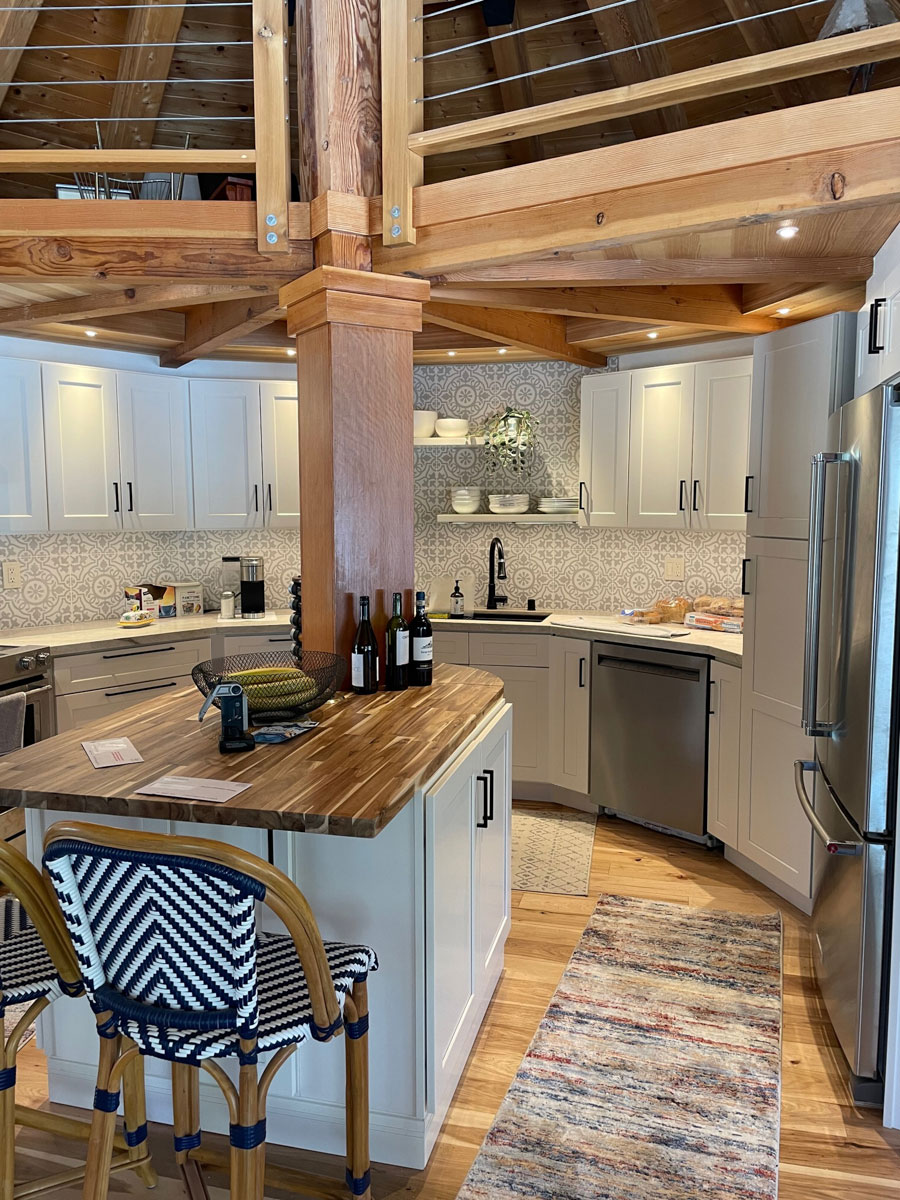 White shaker rustic farmhouse kitchen design in semi-circle shape and center island with wood beam on top and  wood beam ceiling with loft above