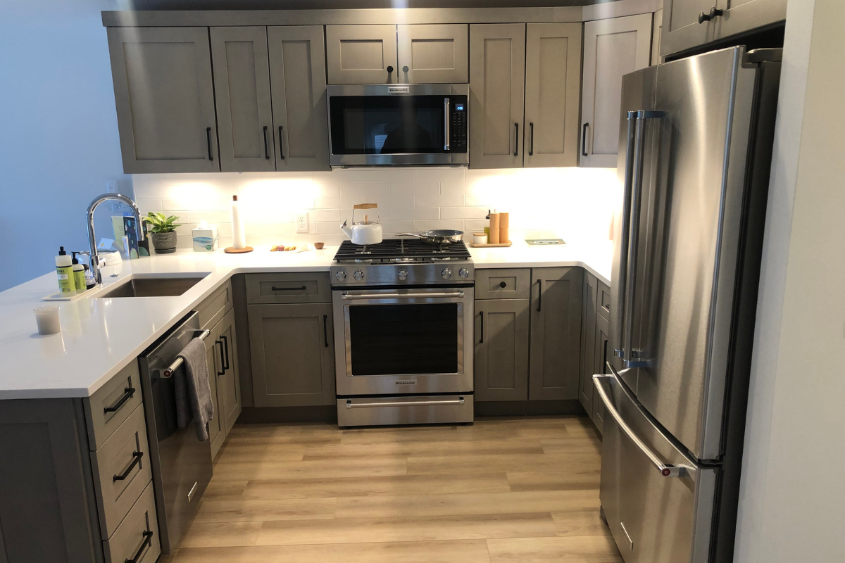 Light gray shaker kitchen design with peninsula and black hardware