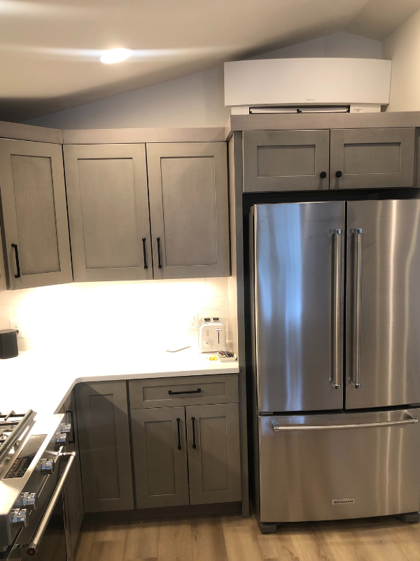 Light gray shaker kitchen design with peninsula and black hardware