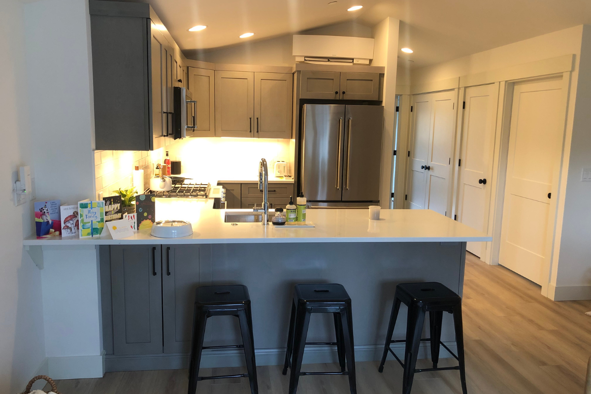 Light gray shaker kitchen design with peninsula and black hardware