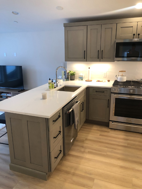 Light gray shaker kitchen design with peninsula and black hardware