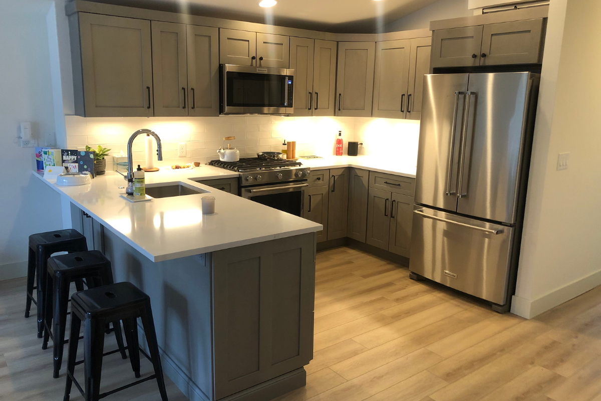 Light gray shaker kitchen design with peninsula and black hardware