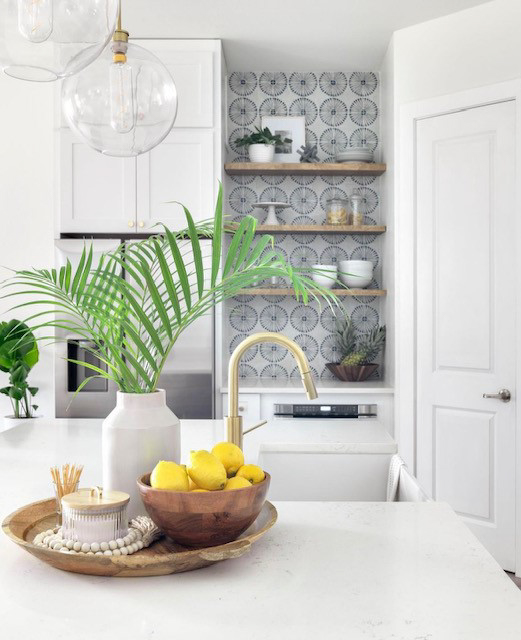 Stacked white shaker kitchen cabinets with gold cabinet hardware and a navy blue island with white quartz countertops 