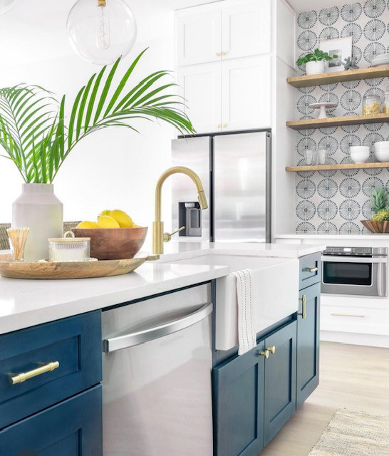 Stacked white shaker kitchen cabinets with gold cabinet hardware and a navy blue island with white quartz countertops 