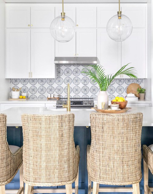 Stacked white shaker kitchen cabinets with gold cabinet hardware and a navy blue island with white quartz countertops 