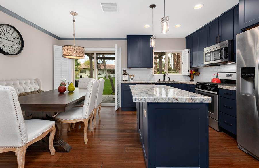 L-shaped blue shaker kitchen with white granite countertops next to large dining room table