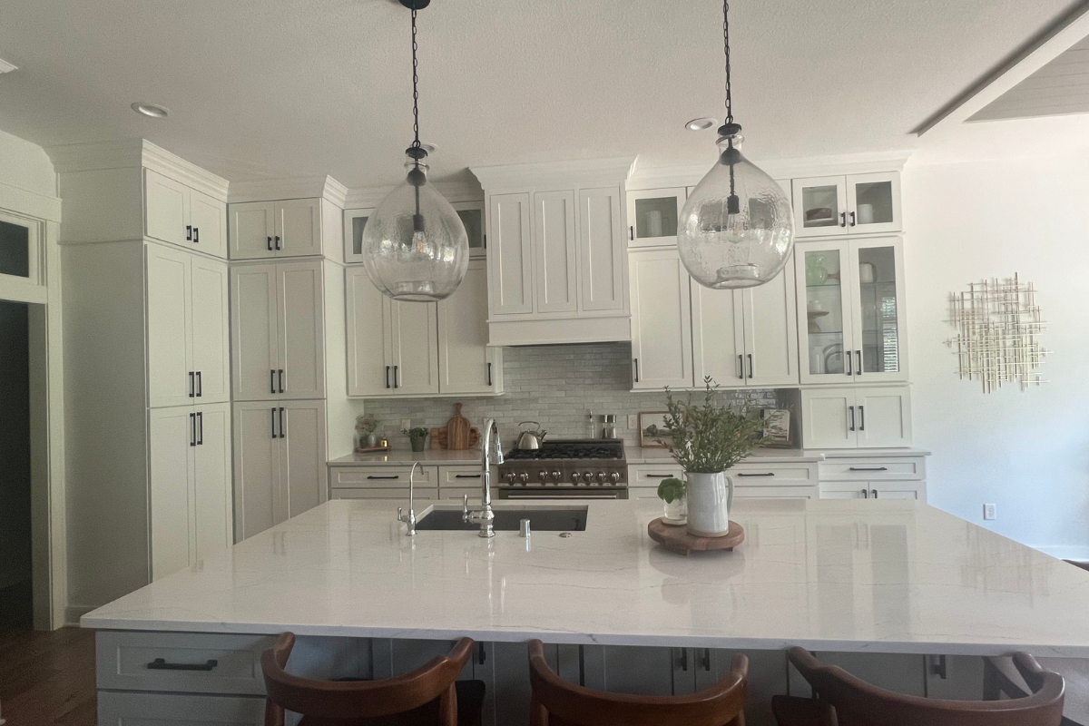 Stacked glass white shaker kitchen cabinets with a medium-gray shaker island and white quartz countetops