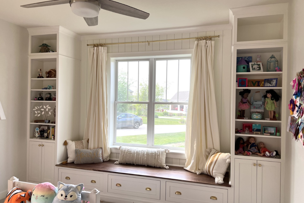 White inset shaker cabinets designed as a built-in reading nook and bookcase with decorative crown molding and cup pulls.