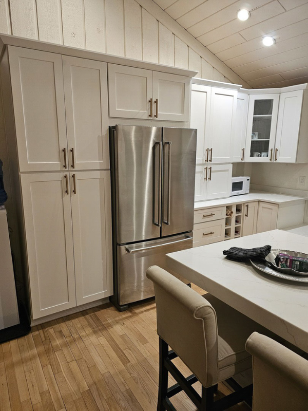 L-shaped white shaker kitchen remodel and kitchen island with white quartz countertops and white wall paneling