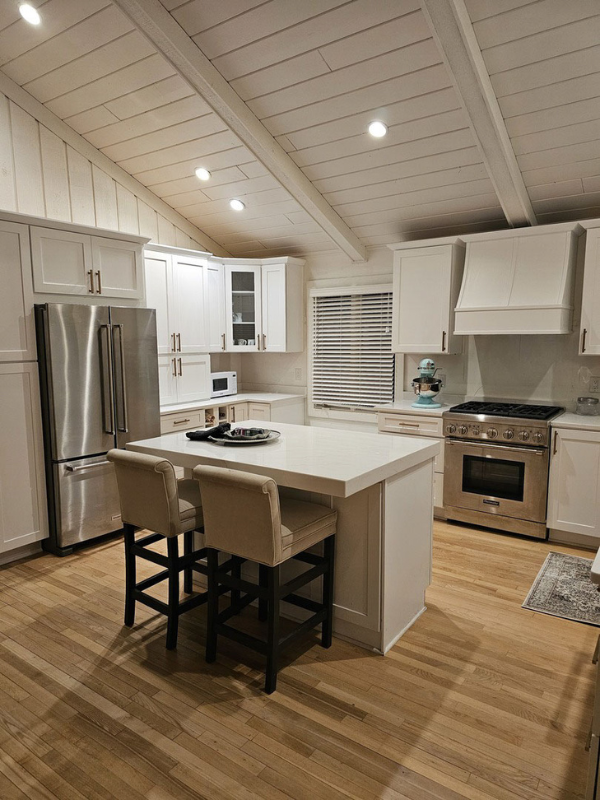 L-shaped white shaker kitchen remodel and kitchen island with white quartz countertops and white wall paneling