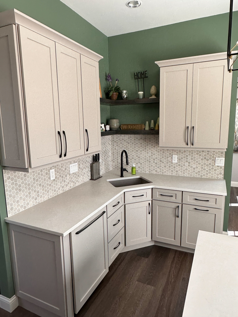 Light gray shaker kitchen cabinets with a small, decorative island with a built-in bookcase, green walls, and a neutral tile backsplash