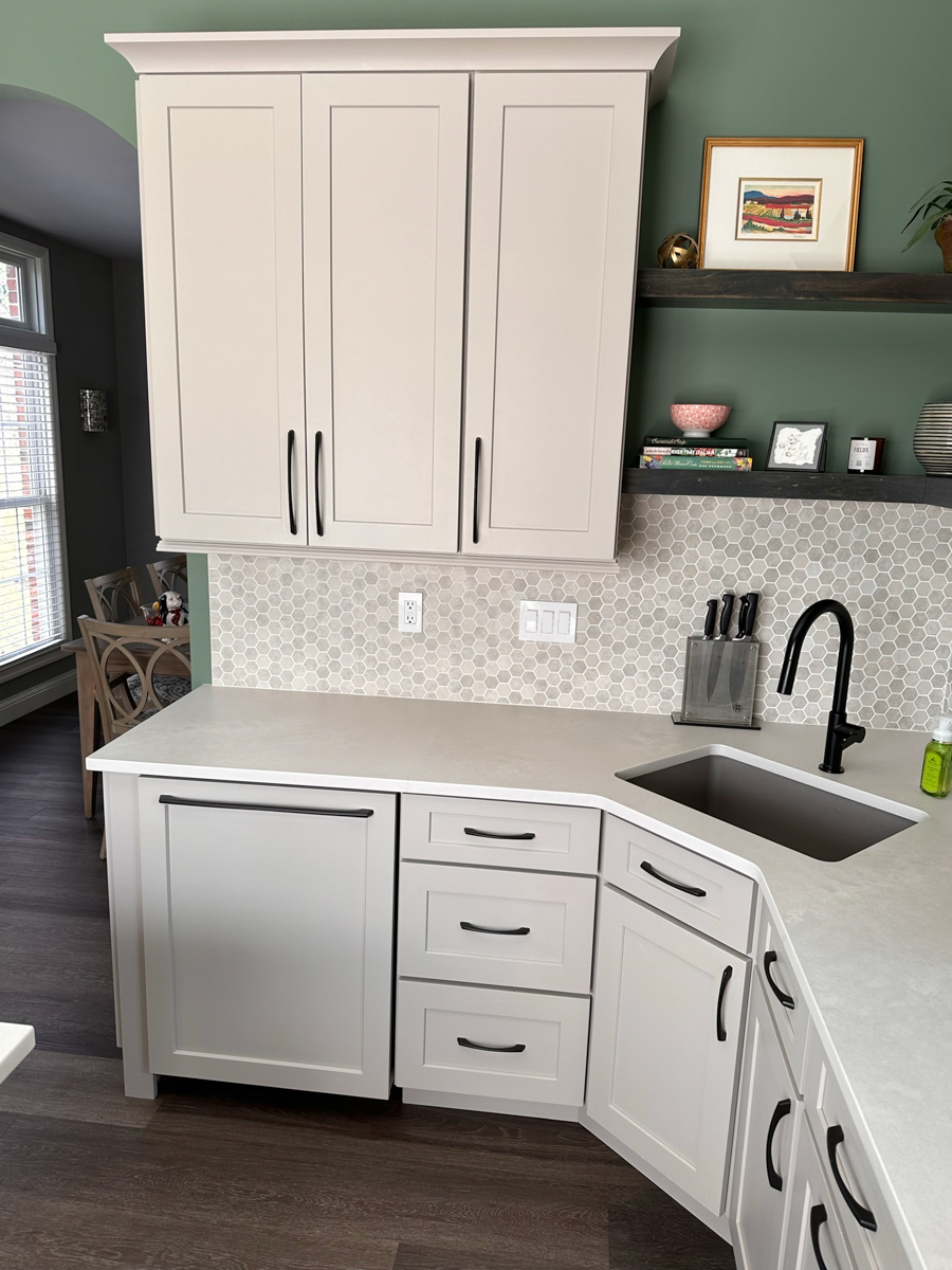 Light gray shaker kitchen cabinets with a small, decorative island with a built-in bookcase, green walls, and a neutral tile backsplash