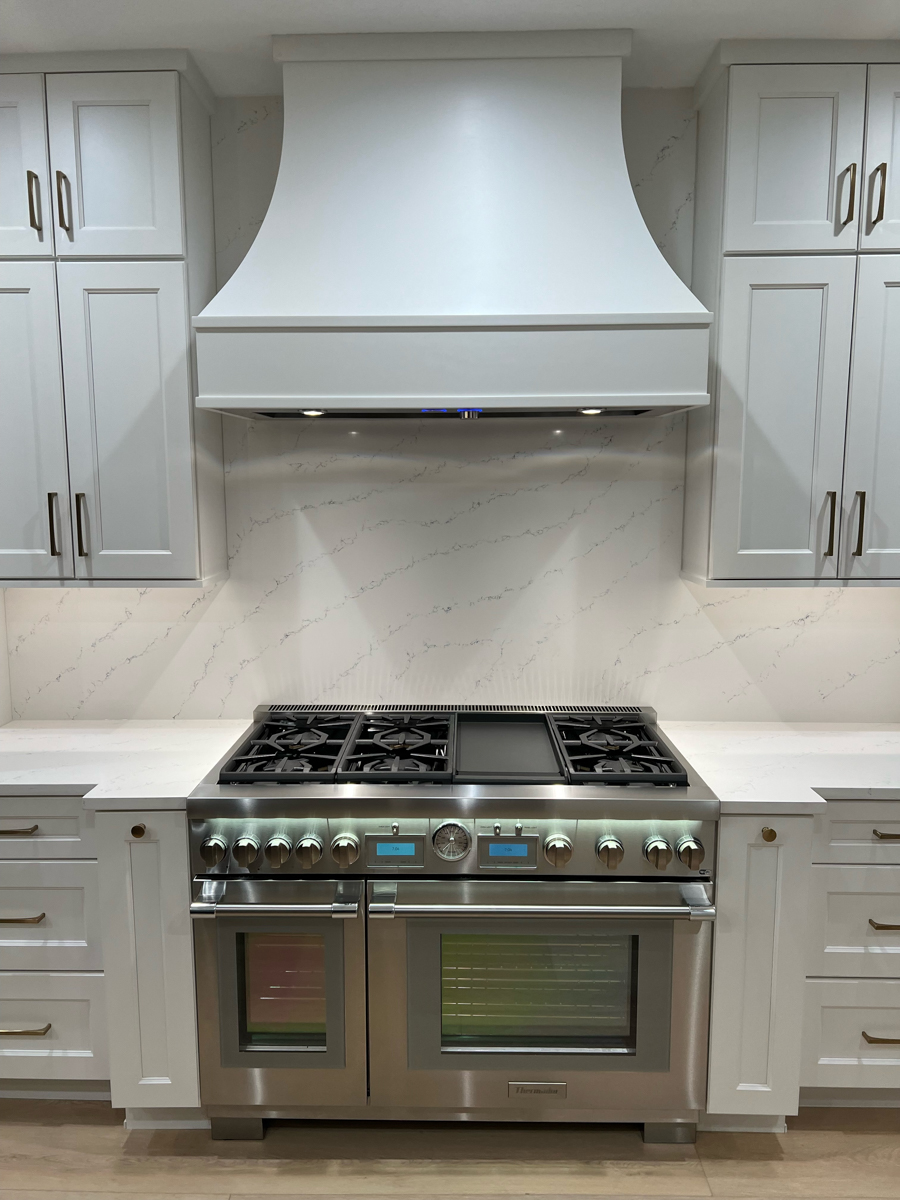 Grand decorative white shaker kitchen design with stacked cabinets, an artisan kitchen hood, and white quartz countertops