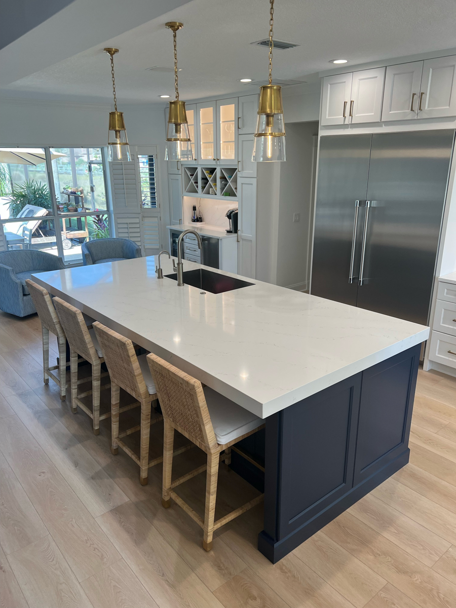 Grand decorative white shaker kitchen design with stacked cabinets, an artisan kitchen hood, navy blue island cabinets, and white quartz countertops