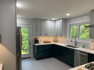 Light gray slab door wall cabinets and navy blue slab door base cabinets with white quartz countertops