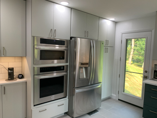 Light gray slab door wall cabinets and navy blue slab door base cabinets with white quartz countertops