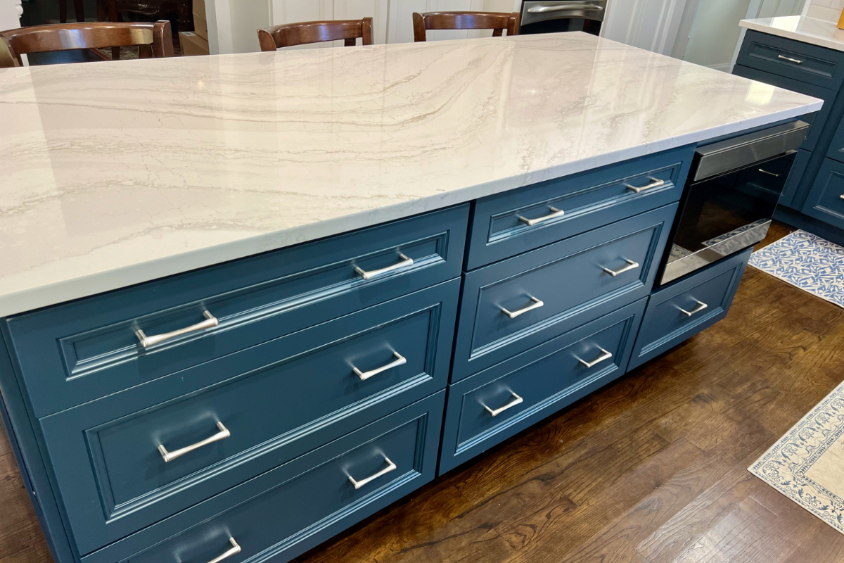 L-shaped decorative white kitchen design with indigo blue island and white quartz countertops