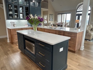 Light wood kitchen cabinets with indigo furniture-style accents and white quartz countertops